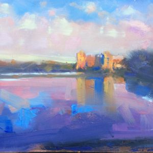 Late Evening Light at Carew Castle with a blue colourful mill pond and castle glowing orange with the Sunlight
